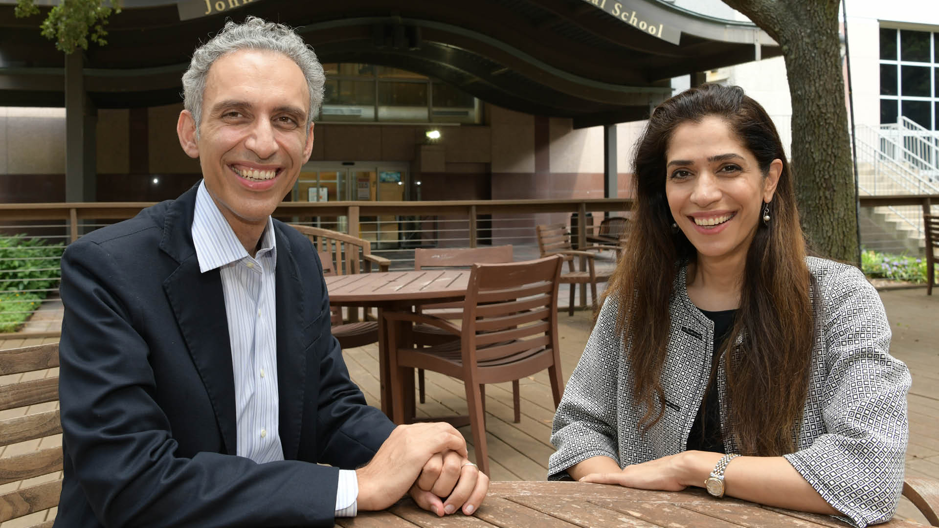 Drs. Faraz Bishehsari and Mahboobeh Mahdavinia meet outdoors on campus, engaged in a focused, collaborative discussion, surrounded by greenery and university buildings in a casual academic setting
